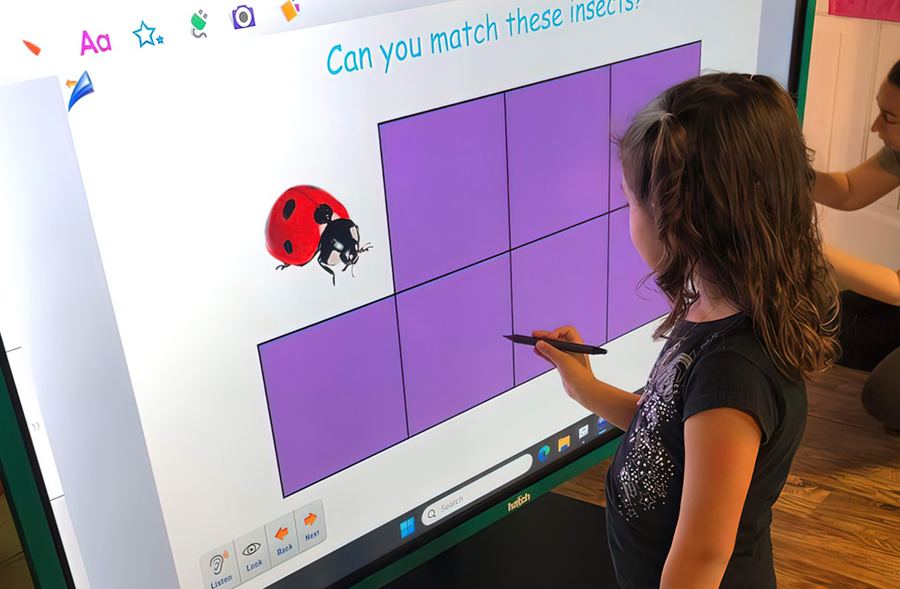 A teacher leading a pre-K lesson on the interactive board